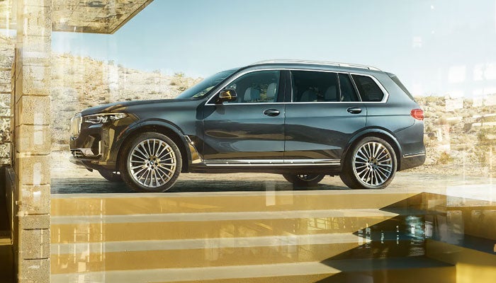 A blue metallic BMW X7 parked above gold steps.